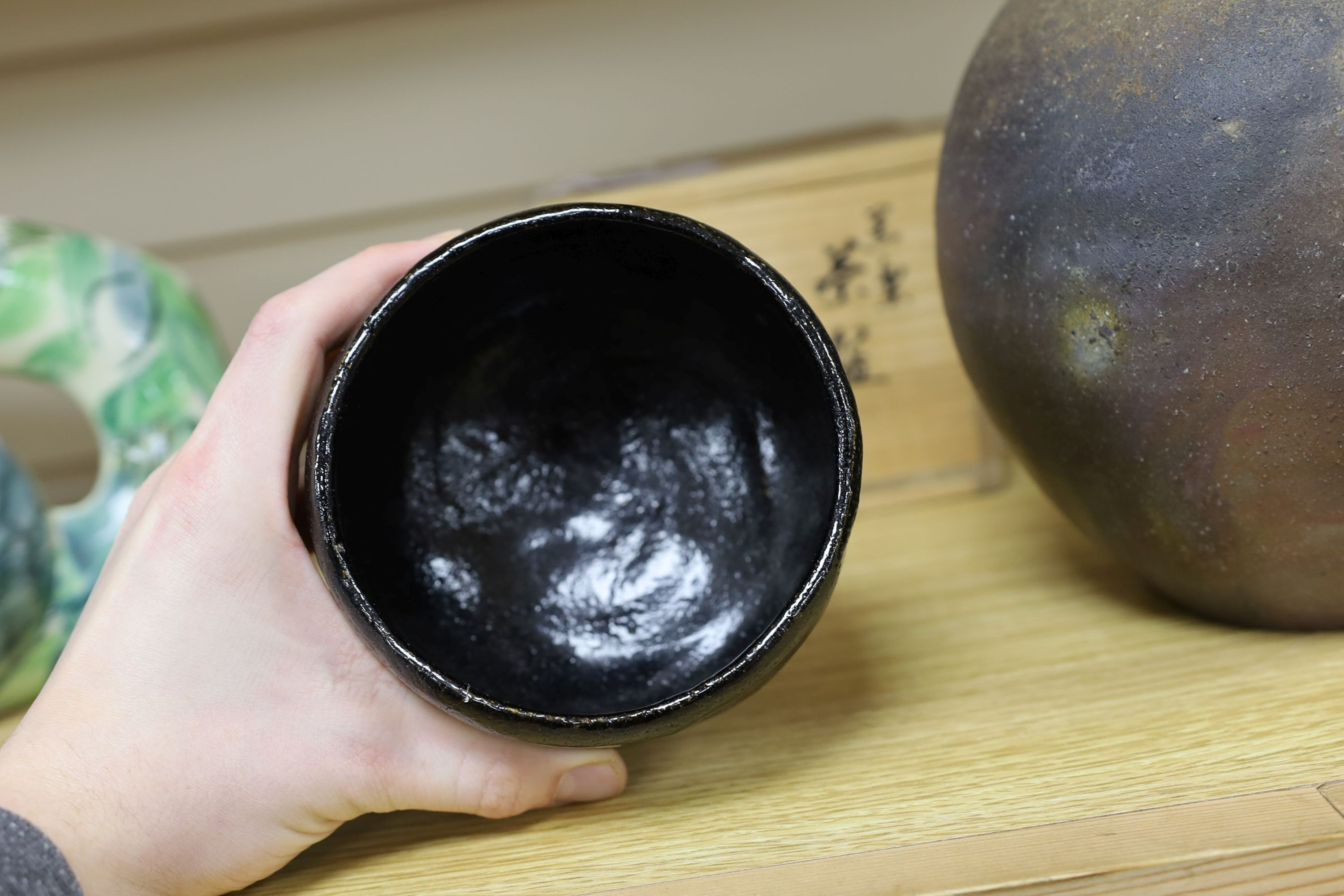 Japanese studio pottery: a boxed black glaze stoneware unomi tea bowl, with impressed mark, together with a ovoid vase, marked, 21cm tall
